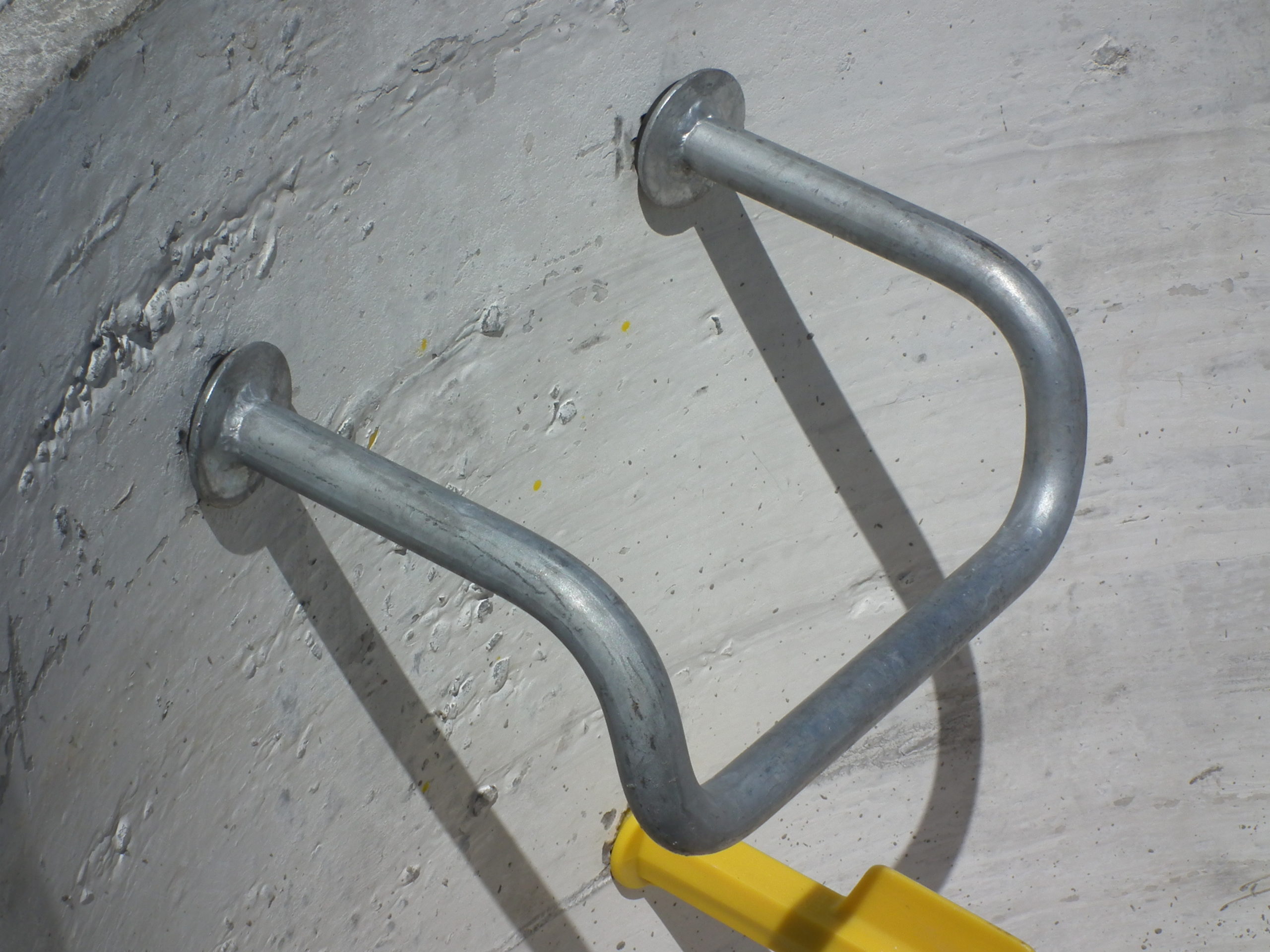 Galvanised steel manhole step with slip-resistant tread for concrete installation.