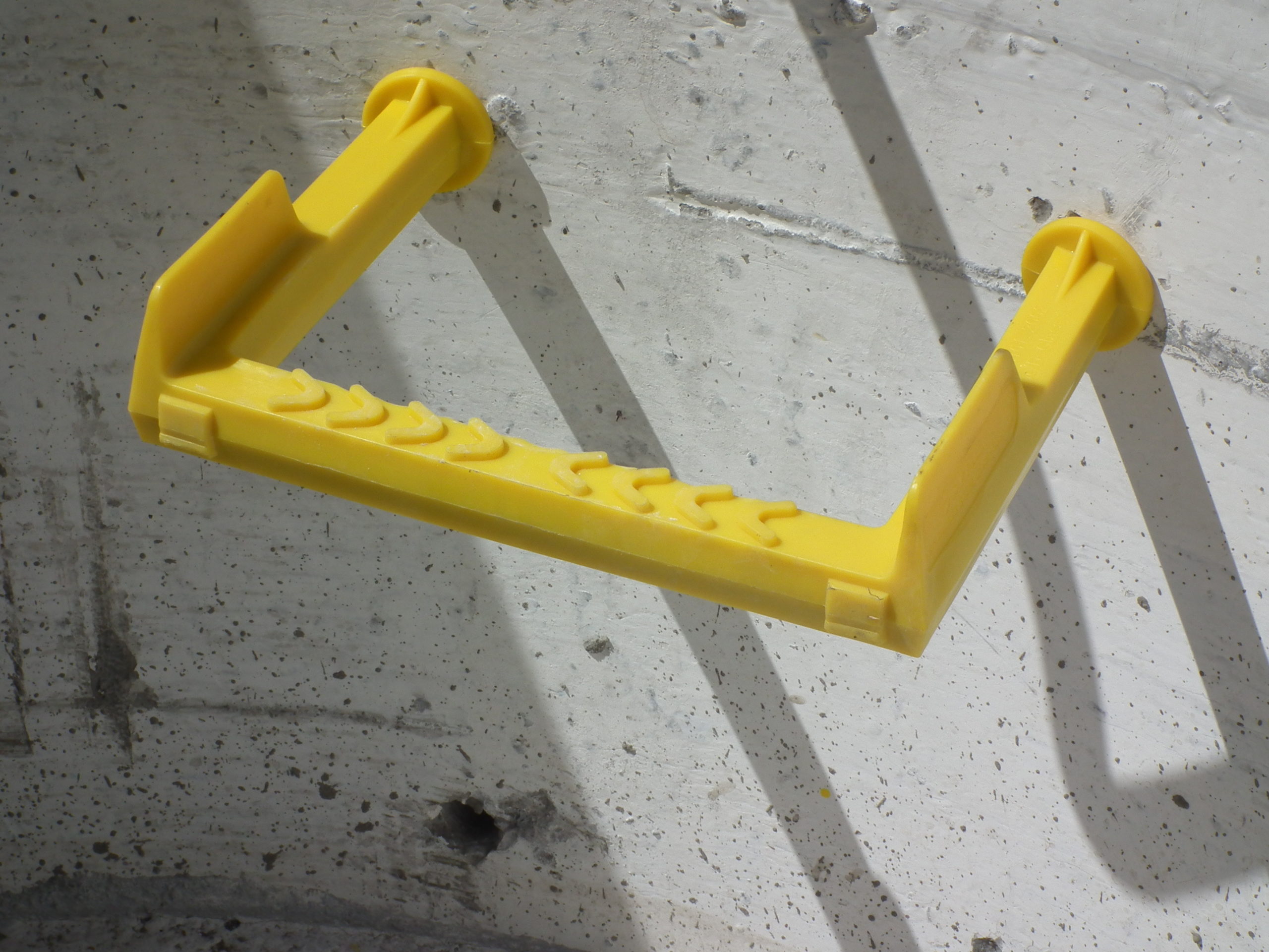 Yellow nylon-encapsulated manhole step with steel core for enhanced grip and visibility.